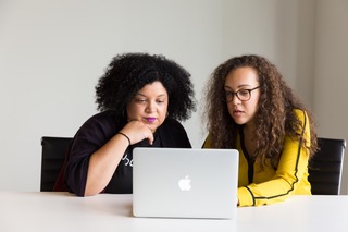 Two women looking at a Macbook