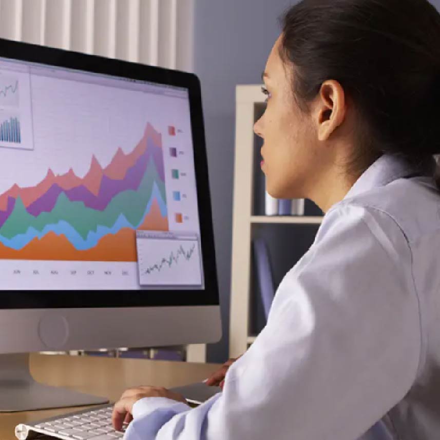 A woman looking at a series of graphs on a computer monitor