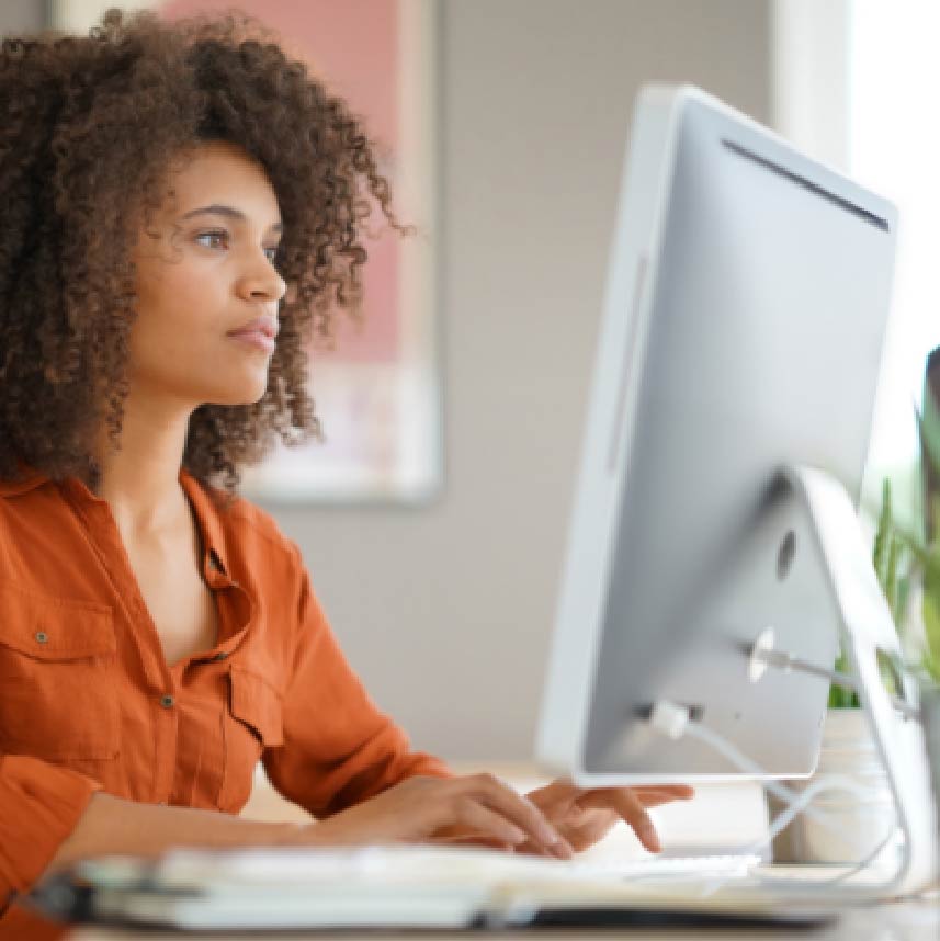 A woman, seated, working at a computer