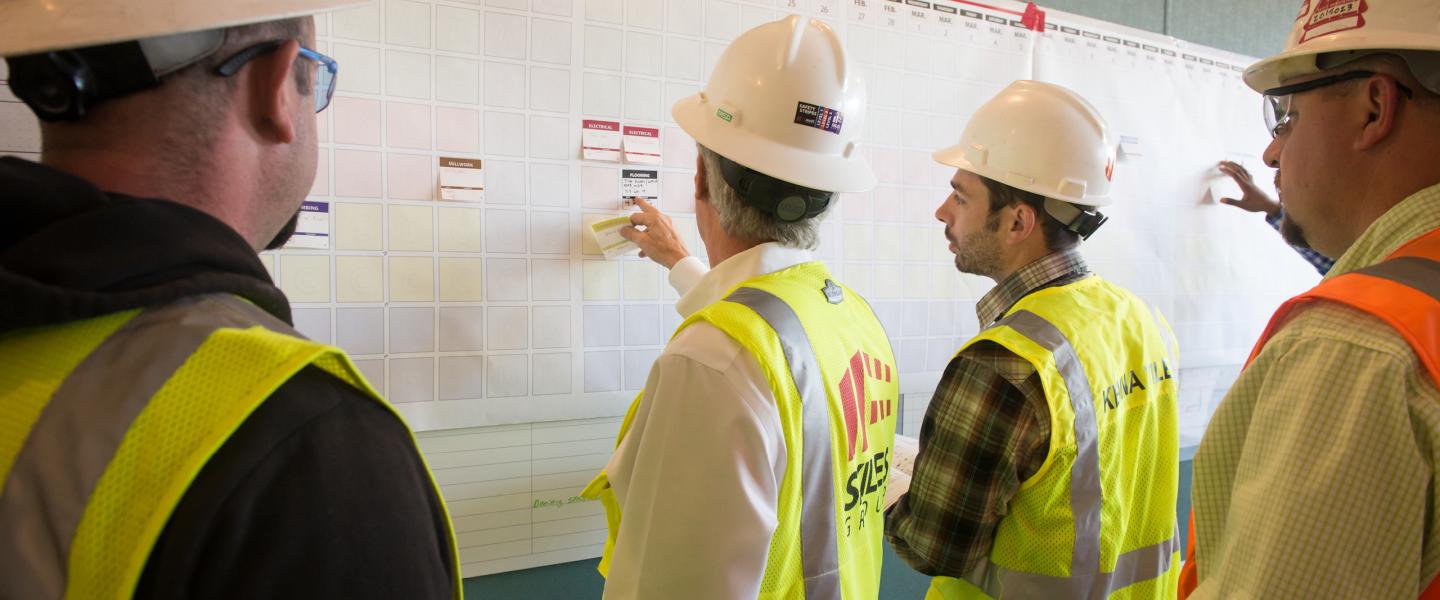 Construction workers in hard hats working on a whiteboard