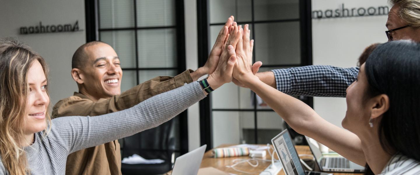 Employees high-fiving at a meeting