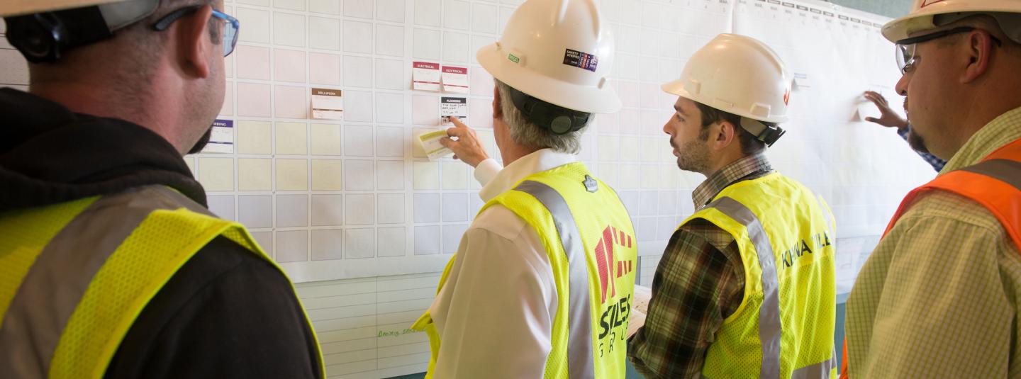 Construction workers in hard hats working on a whiteboard