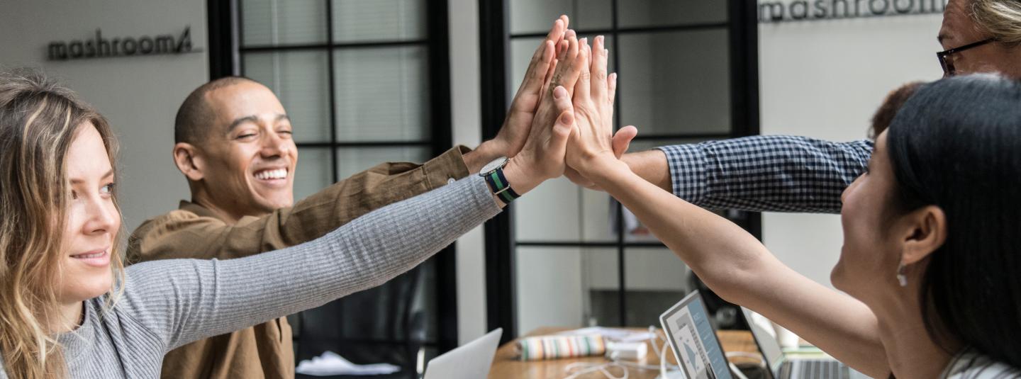 Employees high-fiving at a meeting