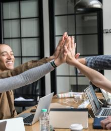 Employees high-fiving at a meeting