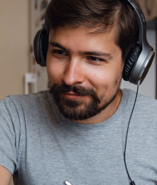 A smiling man wearing a headset looking at a computer monitor